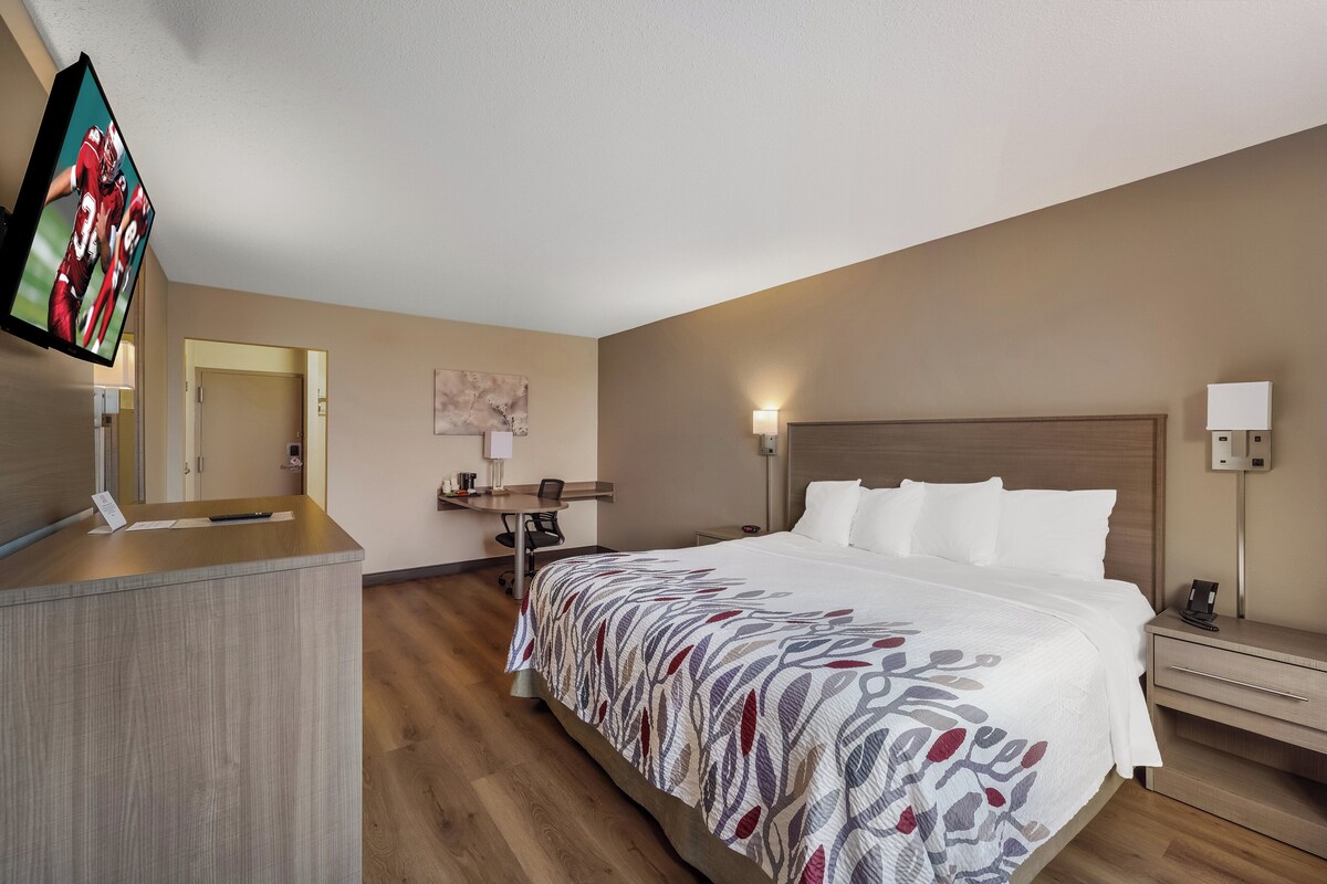 A hotel room with a bed, desk, and TV.
