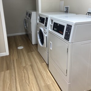 A laundry room with two front-loading washing machines and a dryer.