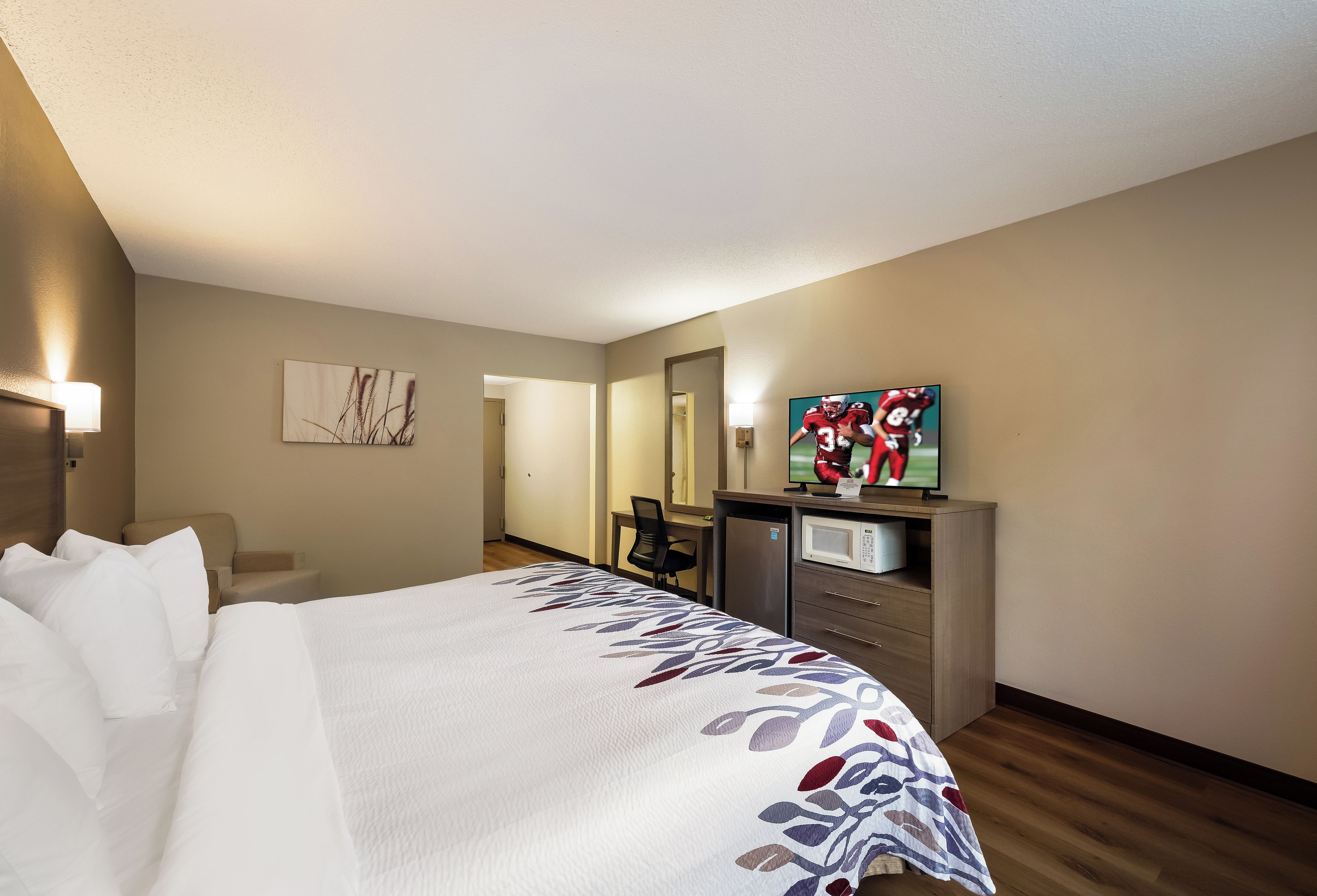 Ein Hotelzimmer mit Bett, Schreibtisch mit Computer, Fernseher und Mikrowelle.