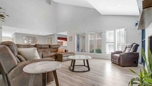 A spacious living room with a large sectional sofa, a round coffee table, and a recliner. - Luxurious Tree House (Lubbock)