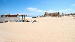 A beach with a wooden structure, a building with multiple balconies, and a clear sky. - 2 bedroom beach front home in Orihuela Costa (Orihuela Costa)
