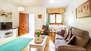A living room with a sofa, a coffee table, a TV, and a dining area with a table and chairs. - 2 bedroom beach front home in Orihuela Costa (Orihuela Costa)