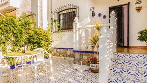 A courtyard with a white table and chairs, a stone wall, and a tiled floor. - 2 bedroom beach front home in Orihuela Costa (Orihuela Costa)