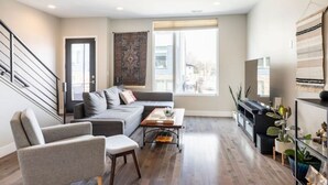 Una sala moderna con un sofá gris, una mesa de centro y un mueble para la televisión.