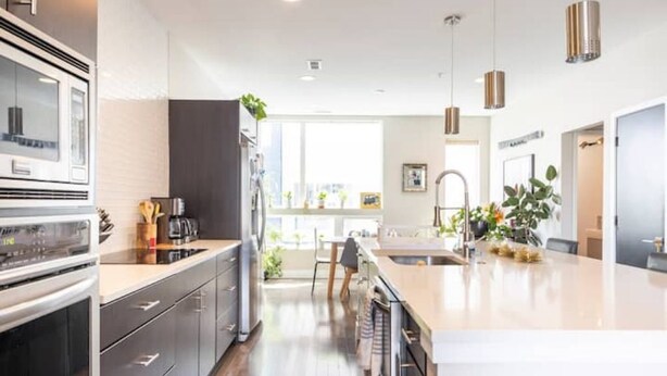 Una cocina moderna con una isla central, electrodomésticos integrados e iluminación colgante.