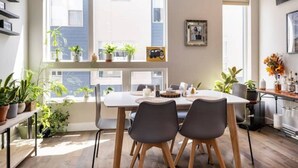 Un comedor moderno con un amplio ventanal, plantas en macetas y una mesa lista para dos personas.
