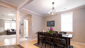 A dining area with a wooden table and chairs, a chandelier, and a view of a living room. - Gray Corner Place | Walk Score 90 | Sleeps 9 (Washington)