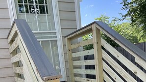 A wooden staircase with a handrail leading to a deck area. - Gray Corner Place | Walk Score 90 | Sleeps 9 (Washington)