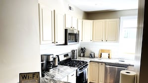 A kitchen with white cabinets, a stove, a microwave, and a Wi-Fi sign. - Gray Place | Walk Score 90 | Sleeps 12 (Washington)