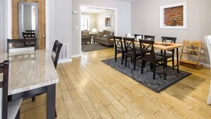 A modern dining area with a wooden table and chairs, a patterned rug, and a brick accent wall. - Gray Place | Walk Score 90 | Sleeps 12 (Washington)