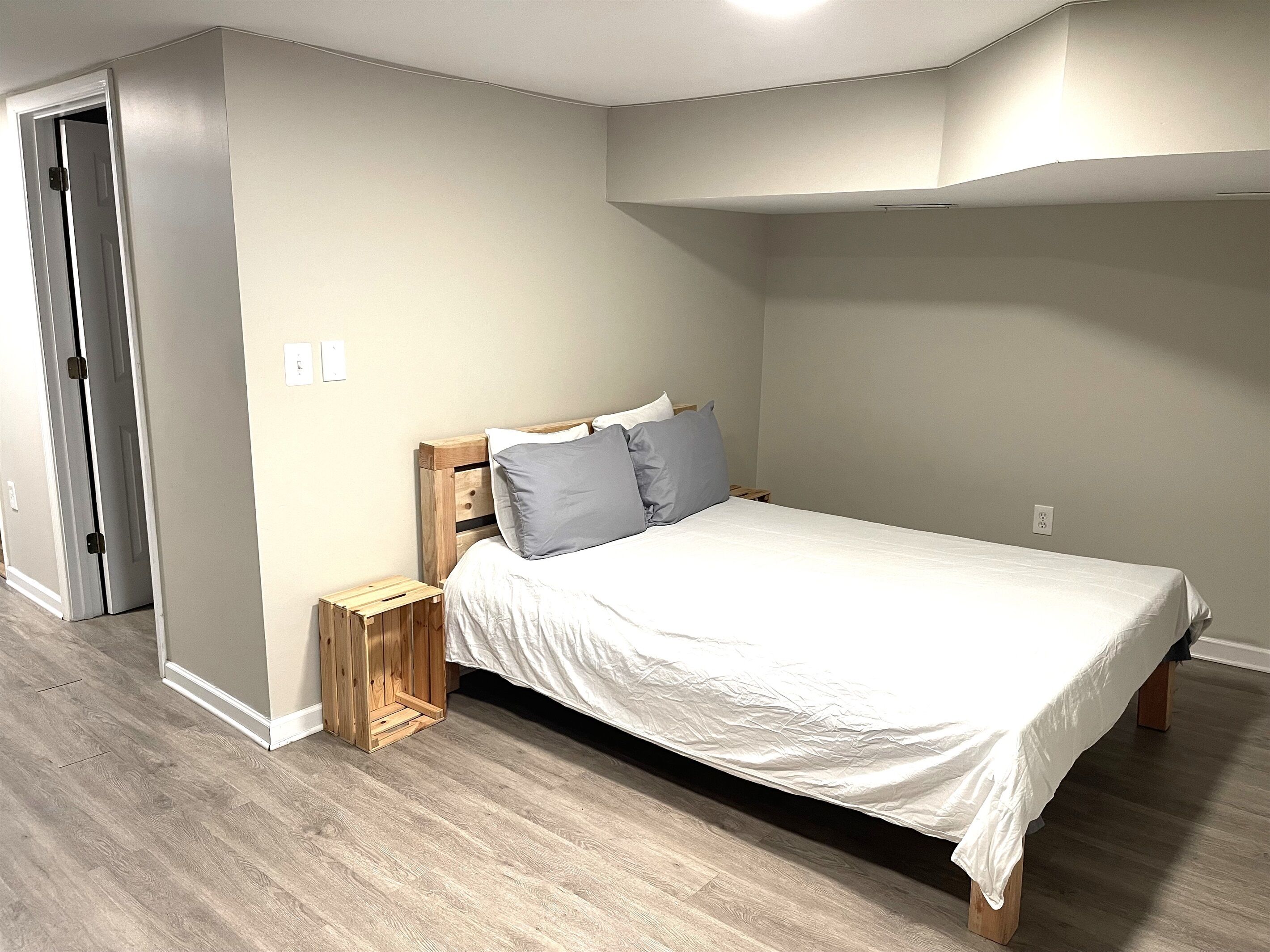 Une chambre à coucher avec un lit en bois, du linge de lit blanc et une petite table de chevet en bois.