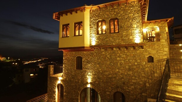 A stone building with arched windows and a balcony, illuminated at night. - Archontiko Polyzos 13 Menda (Volos)