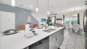 A modern kitchen with a central island, stainless steel appliances, and pendant lighting. - Frozen, Spiderman and Mickey Rooms, Private Pool! (Kissimmee)