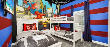 A bedroom with two beds, a bunk bed, a Spider-Man mural, and a cityscape wall.