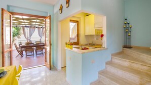 A bright kitchen with yellow cabinets, a sink, and a dining area with wooden chairs and a table.
