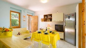 A compact kitchen with a dining area, a refrigerator, and a television.