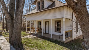 A two-story house with a porch, large windows, and a small deck. - Game Themed, sleeps 12, king beds, walking distance to downtown & splash pad! (Harrison)