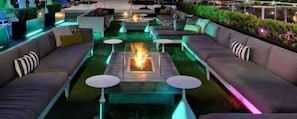 A lounge area with sofas, round tables, and a central fire feature.