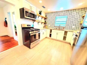 Kitchen area with modern appliances, light cabinetry, and a patterned backsplash.
