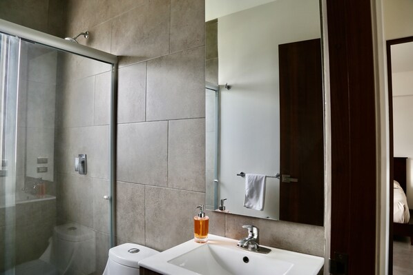 Une salle de bain moderne avec une douche à parois de verre, un lavabo blanc et un grand miroir.