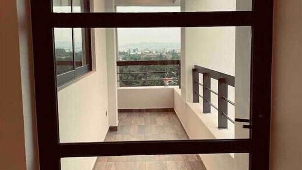 Een smalle gang die uitkomt op een balkon met uitzicht op een stadsbeeld.