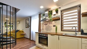 A modern kitchen with a wooden countertop, white cabinets, and a built-in oven. There is a window with blinds, a sink, and a hanging plant. - Cozy home in Legrad with sauna (Legrad)