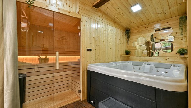 A sauna room with a wooden interior, a glass-enclosed shower area, and a large black hot tub. - Cozy home in Legrad with sauna (Legrad)