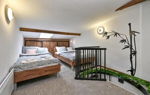 A bedroom with two beds, a skylight, a crib, a wall-mounted plant, and a bamboo decoration. - Cozy home in Legrad with sauna (Legrad)