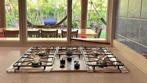 A kitchen with a gas stove, large windows, and a view of a patio with outdoor furniture.