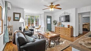 A spacious living room with a ceiling fan, a wooden coffee table, and a television mounted on the wall. - Take me to Italy! an oasis of luxury in central Lubbock (Lubbock)