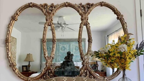 A room with a large ornate mirror, a patterned ottoman, and a vase with flowers. - Take me to Italy! an oasis of luxury in central Lubbock (Lubbock)
