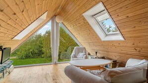Ein gemütlicher Raum mit Holzwänden, einem großen Oberlicht, einer bequemen Couch und einem Esstisch.