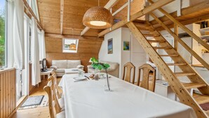 Ein Holzinterieur mit einem für zwei Personen gedeckten Esstisch, einer Couch und einer Treppe.