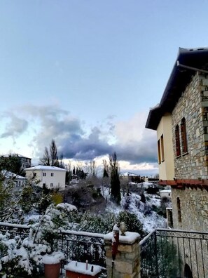 Set amidst snow-covered trees, this charming stone building features a pitched roof and a visible chimney.