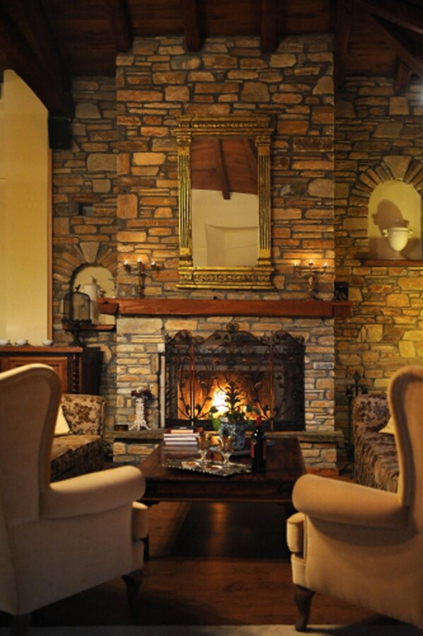 Cozy seating area with a stone fireplace, armchairs, and a mirror.