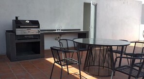 An outdoor patio with a grill, a round table, and four chairs.