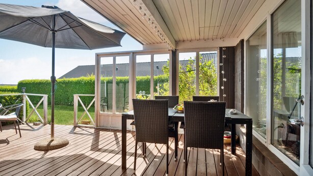 A covered patio with a table and chairs, a large umbrella, and a view of a neatly trimmed hedge and a house in the background. - Awesome home in Slagelse with WiFi (Slagelse)
