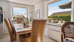 A dining area with a wooden table, leather chairs, and a view of a garden through large windows. - Awesome home in Slagelse with WiFi (Slagelse)