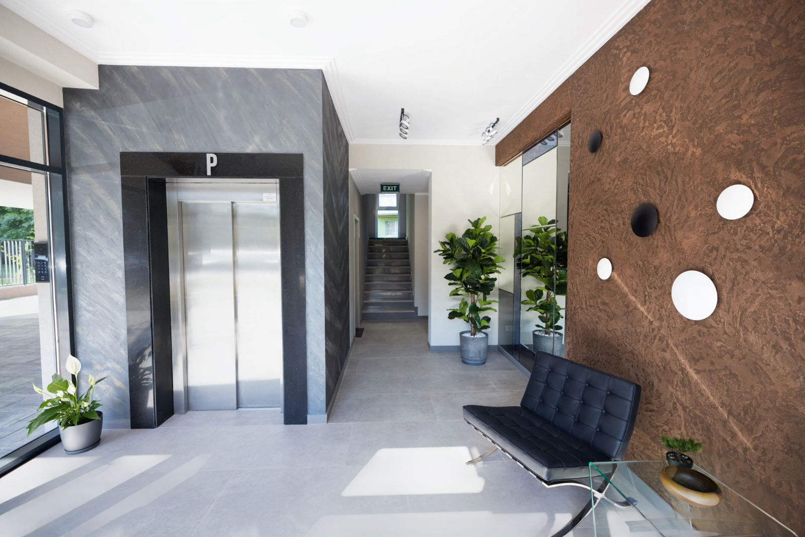 A modern lobby with a reception desk, a seating area, and an elevator.