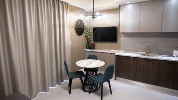 A modern kitchen with a dining area, featuring a round table, chairs, a TV, and a built-in oven.