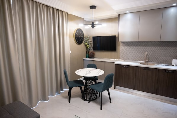 Une cuisine moderne avec un coin repas, comprenant une table ronde, des chaises, un téléviseur et un four encastré.