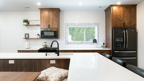 A modern kitchen with wooden cabinets, a large island, a built-in microwave, and a refrigerator. - 38-Acres of Luxury by Notre Dame, 9BR, Indoor Pool (Niles)