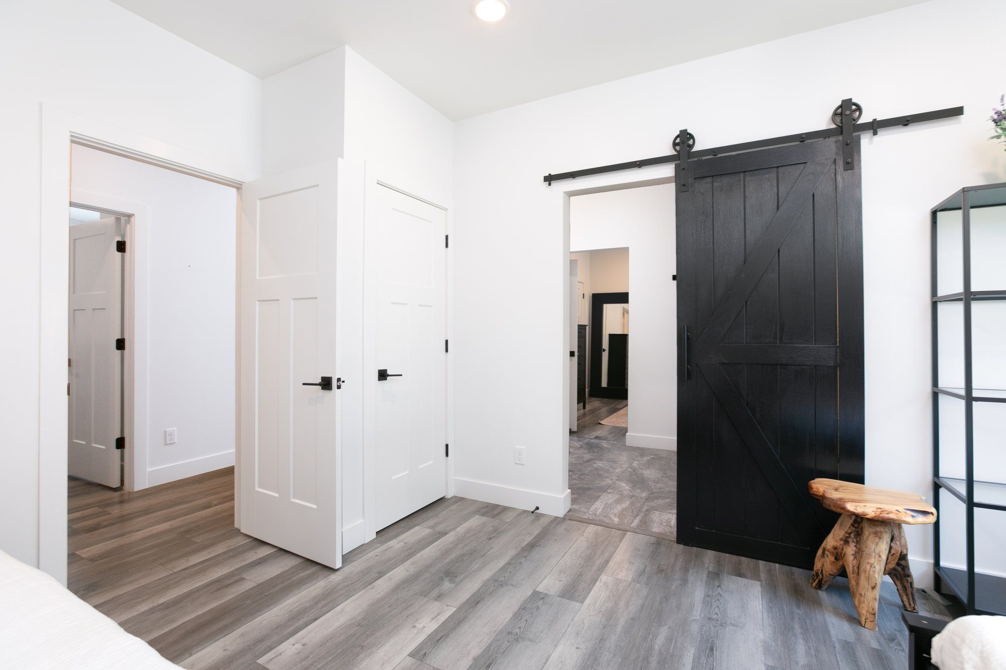 Una habitación con una puerta corredera estilo granero, un pequeño taburete y una estantería.