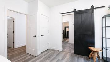 Una habitación con una puerta corredera estilo granero, un pequeño taburete y una estantería.