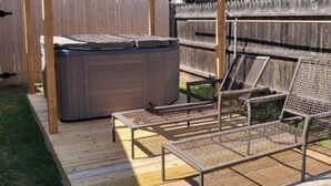 Puuinen terassi, jossa on poreallas, aurinkotuoleja ja pergola.