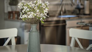 En vase med hvide blomster på et bord i et køkken.