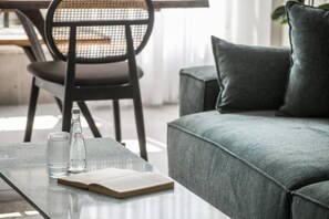 A modern living room with a sofa, a glass coffee table, a book, and a bottle of water. - Spacious & Bright 3BR Apartment (Tel Aviv-Jaffa)