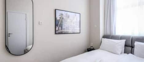 Una habitación de hotel con una cama, una mesita de noche, un espejo y un cuadro en la pared.