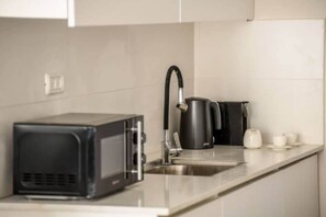 A kitchen with a microwave, kettle, and coffee maker on the counter.