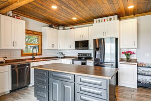 A modern kitchen with white cabinets, stainless steel appliances, and a wooden ceiling. - Family-Friendly Seward Home w/ Sauna & Pool! (Seward)